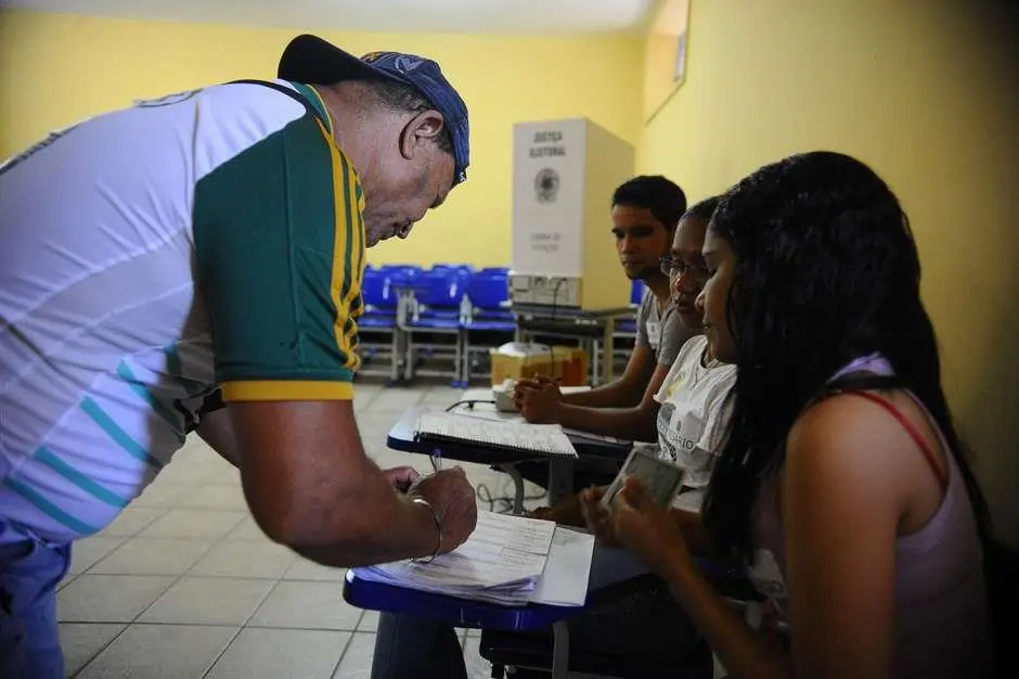 Pessoa escrevendo em uma folha de papel. Texto sobre direitos políticos.