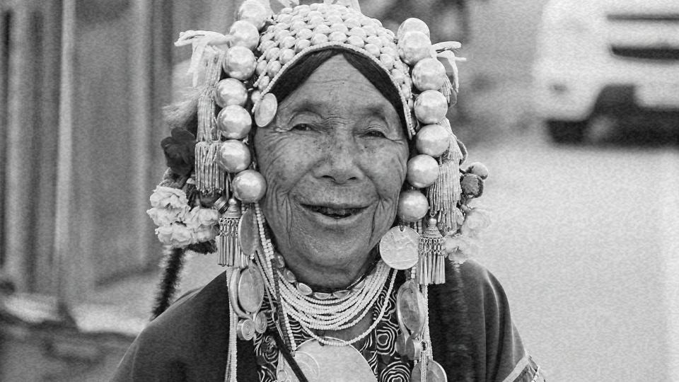 Imagem de uma mulher asiática idosa sorrindo representando o envelhecimento populacional e como os países se preparam para isso