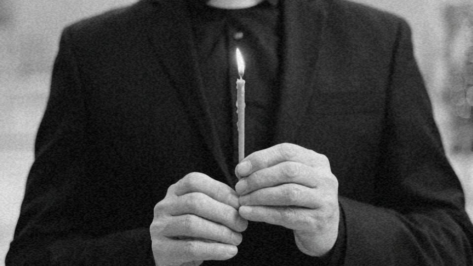 Imagem de uma pessoa em pé segurando uma vela com as suas mãos representando o laicismo e o papel do Estado nisso