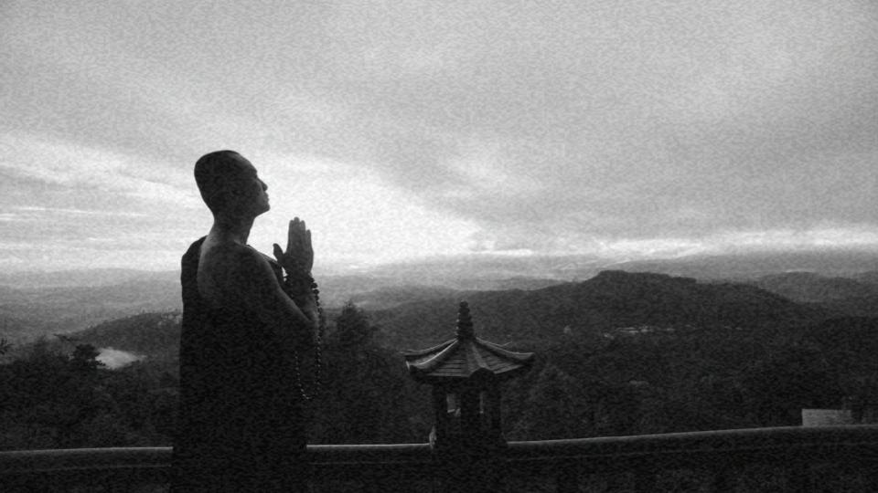 Imagem de um homem em posição de oração olhando para o horizonte montanhoso representando a crença como um direito humano