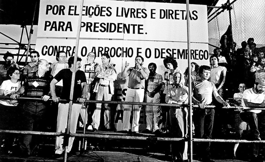 Lula discursa ao lado de outras lideranças no primeiro comício pelas eleições diretas, em 1983. Imagem: Agência Senado.