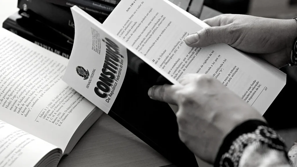 Mãos segurando uma Constituição em uma  imagem em preto e branco 