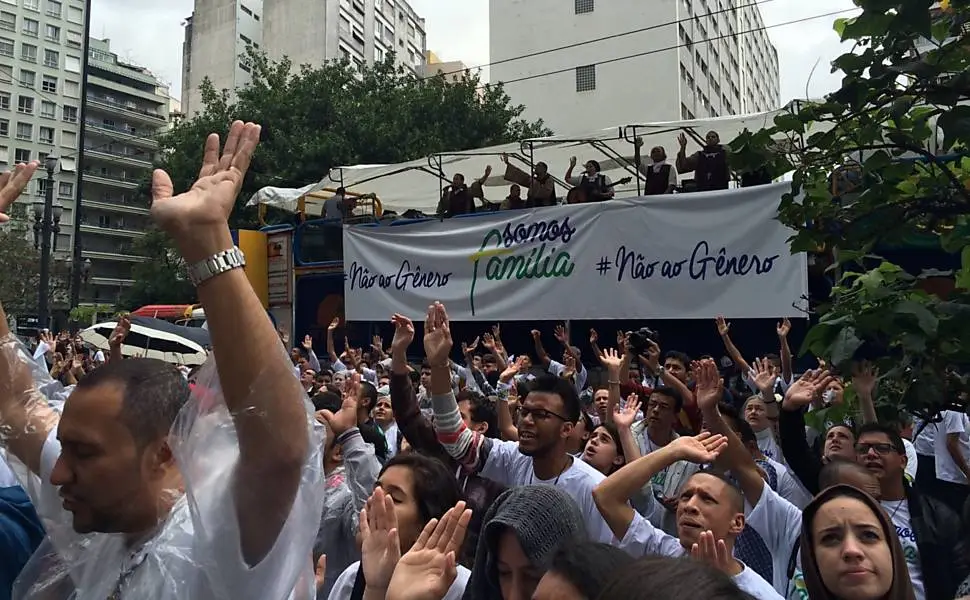 Imagem de manifestação de rua contra "ideologia de gênero", carro de som com faixa escrito "#nãoaogênero somos família"