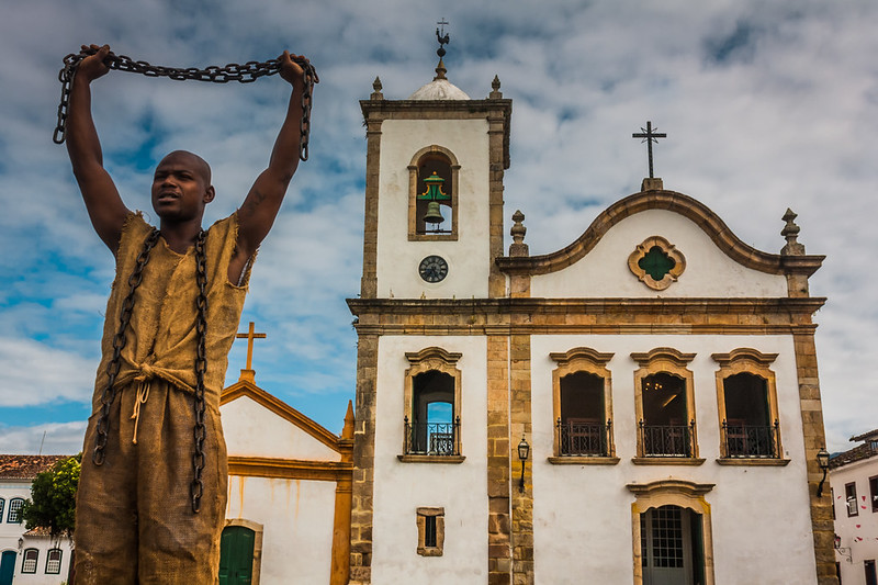 Imagem de um homem negro segurando correntes. Conteúdo sobre as principais violações de direitos humanos.