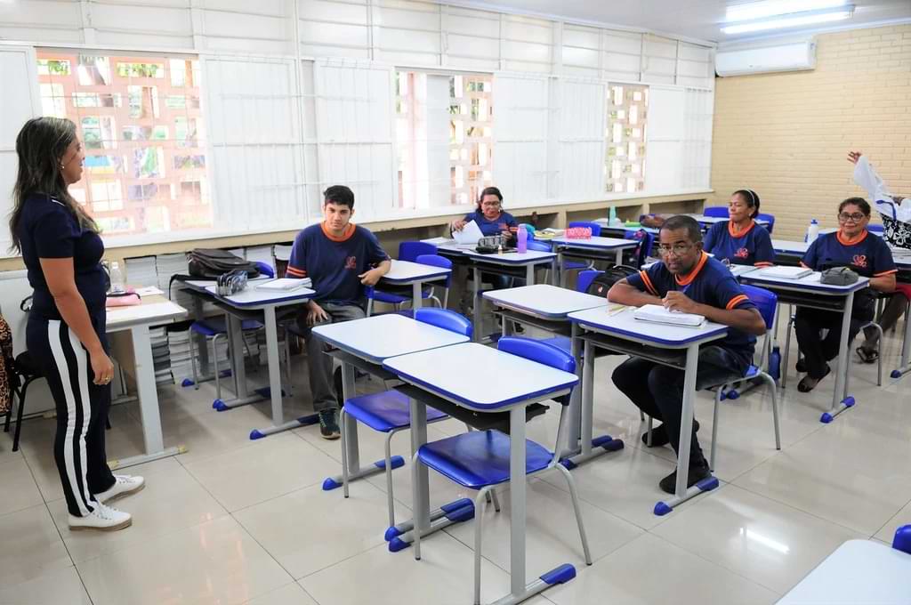 Foto de uma sala de aula com alunos de diversas faixas etárias, uma turma do EJA