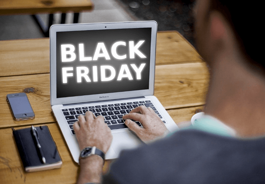 Jovem olhando para a tela de seu computador, onde enxerga os dizeres "Black Friday".