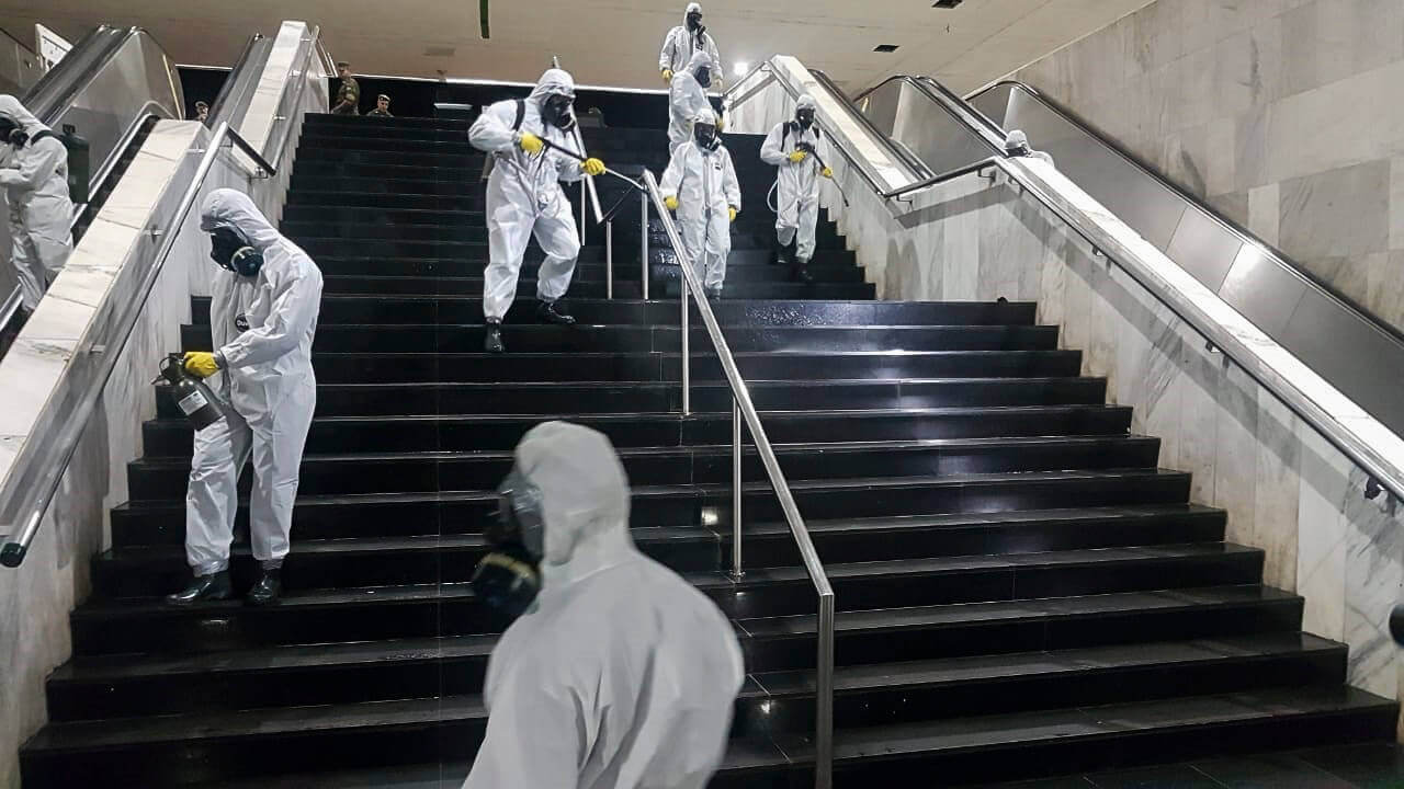 Na imagem, militares com jatos da água limpando as escadas de uma rodoviária. Conteúdo "surto, epidemia e pandemia