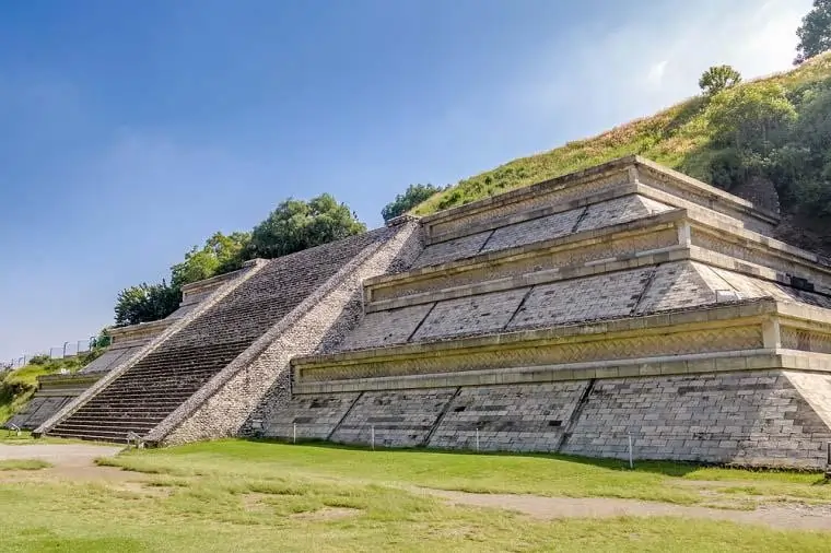 A imagem mostra uma pirâmide com uma escadaria no centro e as laterais com alternancias maiores. O topo é todo reto e liso em toda a sua extensão. Não há portas evidentes na imagem.