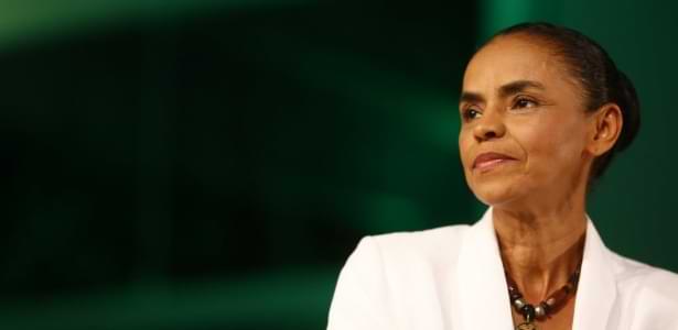 Foto de Marina Silva, mulher negra com 50 anos, usando um coque baixo e um terno branco.