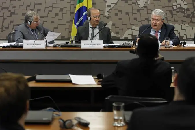 Fotografia de uma sessão de CPI. Na imagem são três senadores compondo a mesa.