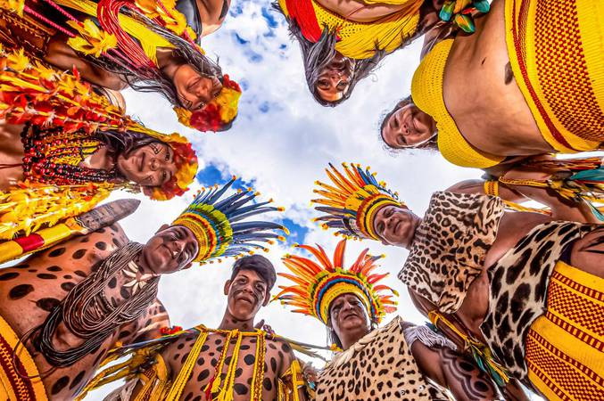 fotografia tirada por baixo de grupo de pessoas indígenas em círculo