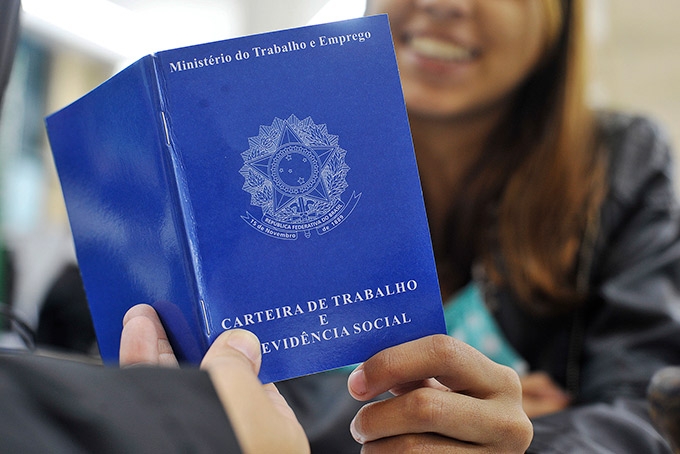 Imagem ilustratitva de inclusão produtiva da juventude. Jovem segurando uma carteira de trabalho.