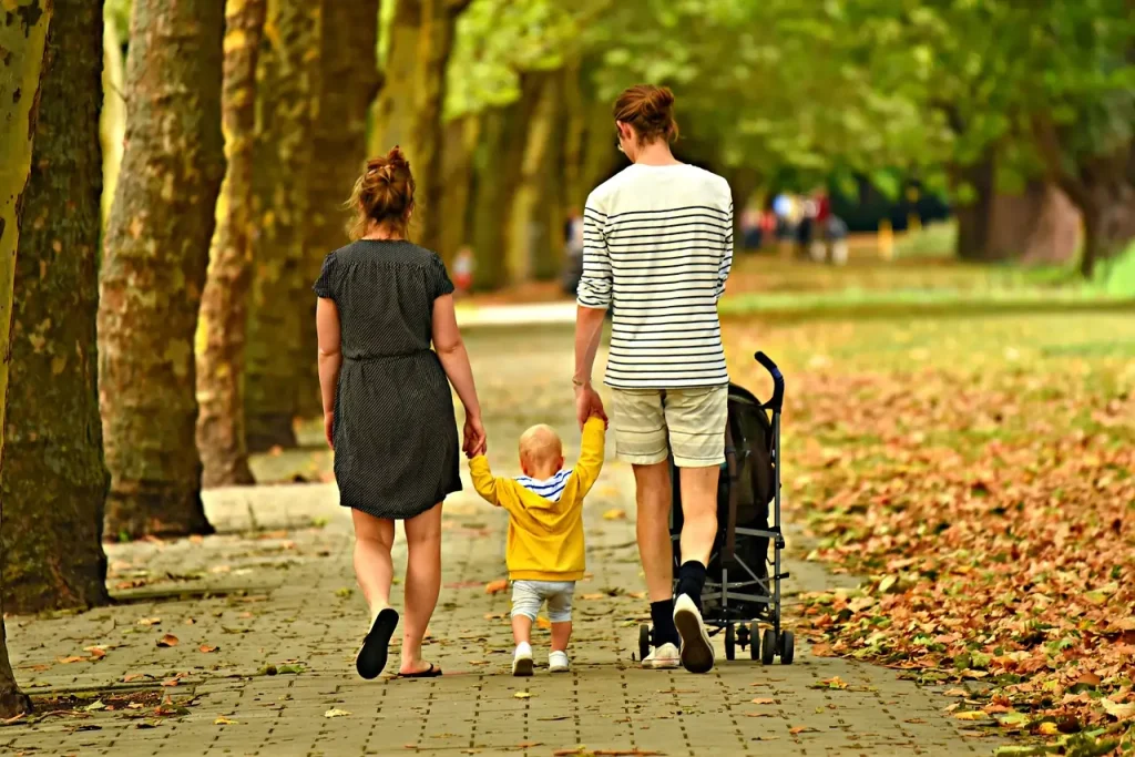 Uma família de duas mães caminhando por um caminho, empurrando um carrinho de bebê, desfrutando de um momento ao ar livre juntos.