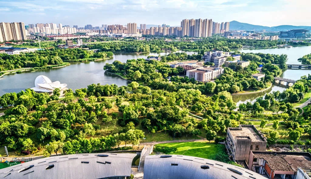 Imagem de uma cidade com muitos prédios, moderna e com área verde bem preservada, representando o conceito de cidade sustentável.