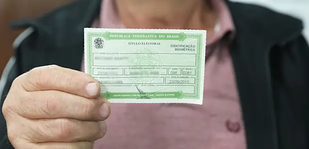 Pessoa segurando título de eleitor, documento para votar