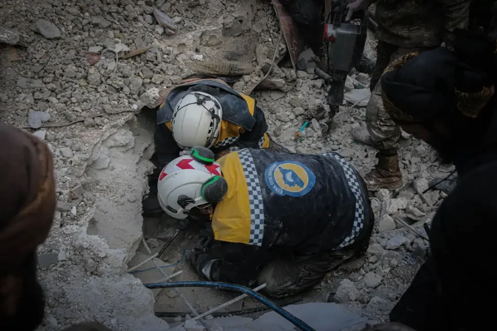 Homens da defesa civil trabalhando em um salvamento em meio a escombros.