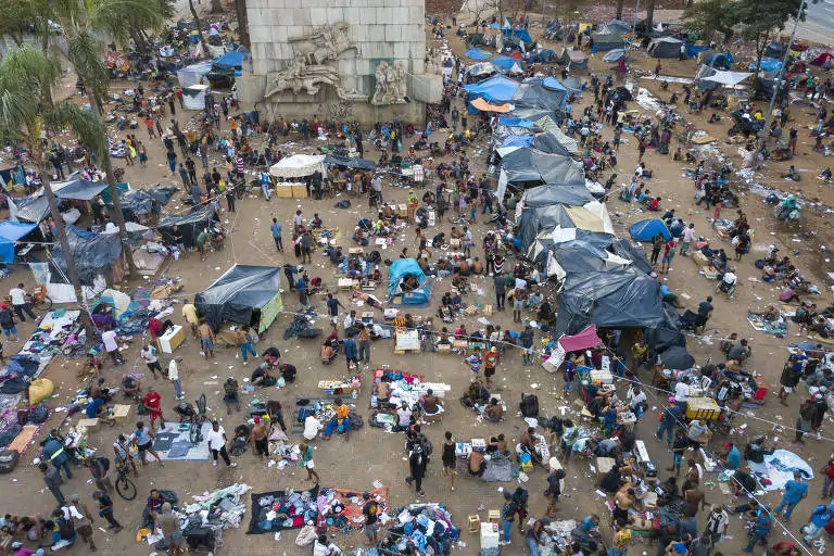 Rua com diversas pessoas em situação de rua e que transitam pela área da Cracolândia. Via em condições precárias de infraestrutura e saneamento básico.