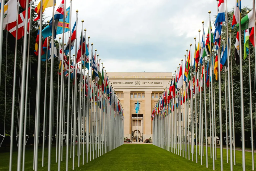 Prédio das Nações Unidas ao fundo e bandeiras de diversos países à frente. Texto: COP30: Uma Década do Acordo de Paris e os Desafios do Clima