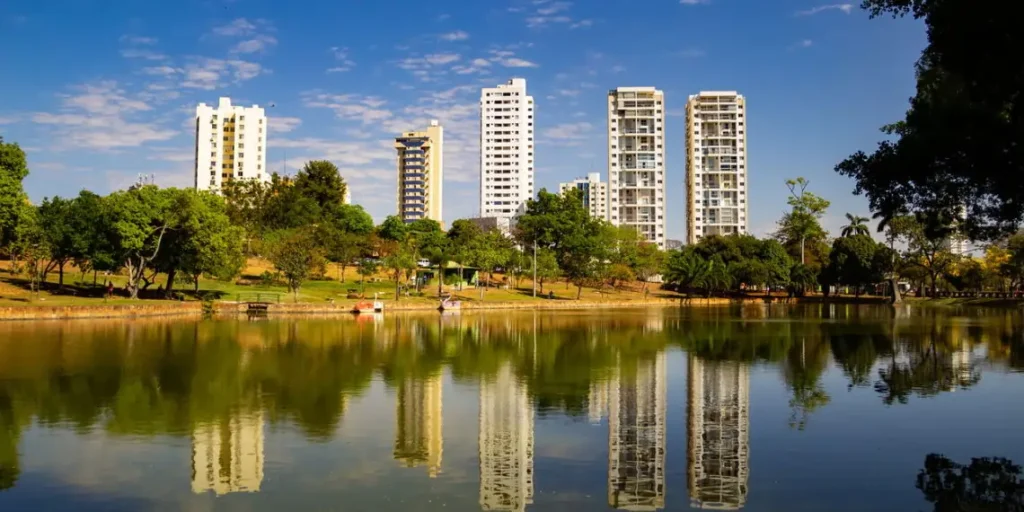 Imagem da cidade de Goiânia, de uma parque com seis prédios altos ao fundo em um dia ensolarado, aparentando estar calor. Saúde no Centro-Oeste