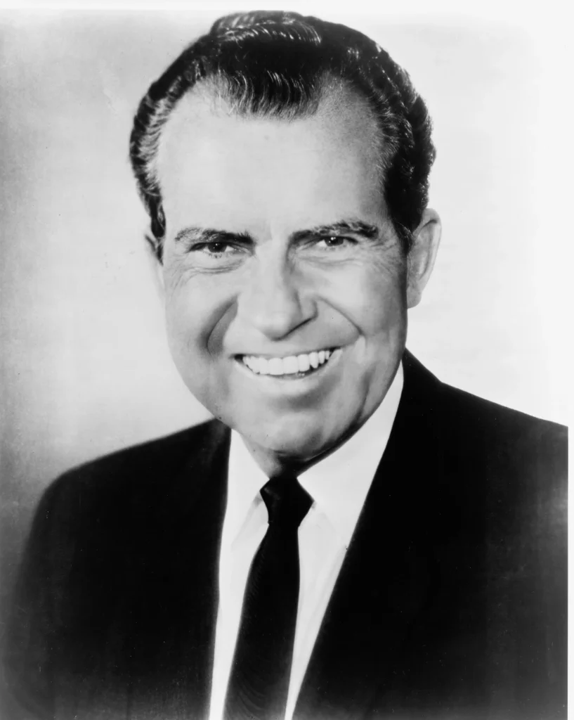 Imagem de Richard Nixon sorrindo. Homem branco, de cabelo escuro, curto. Texto: Quem foi Richard Nixon?