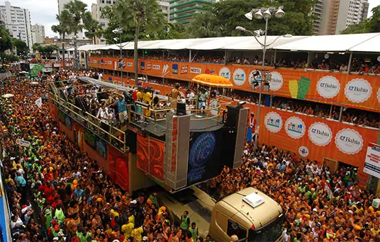 Imagem de um trio elétrico rodeado pelo público, em Salvador. Texto: Tipos de carnaval no Brasil